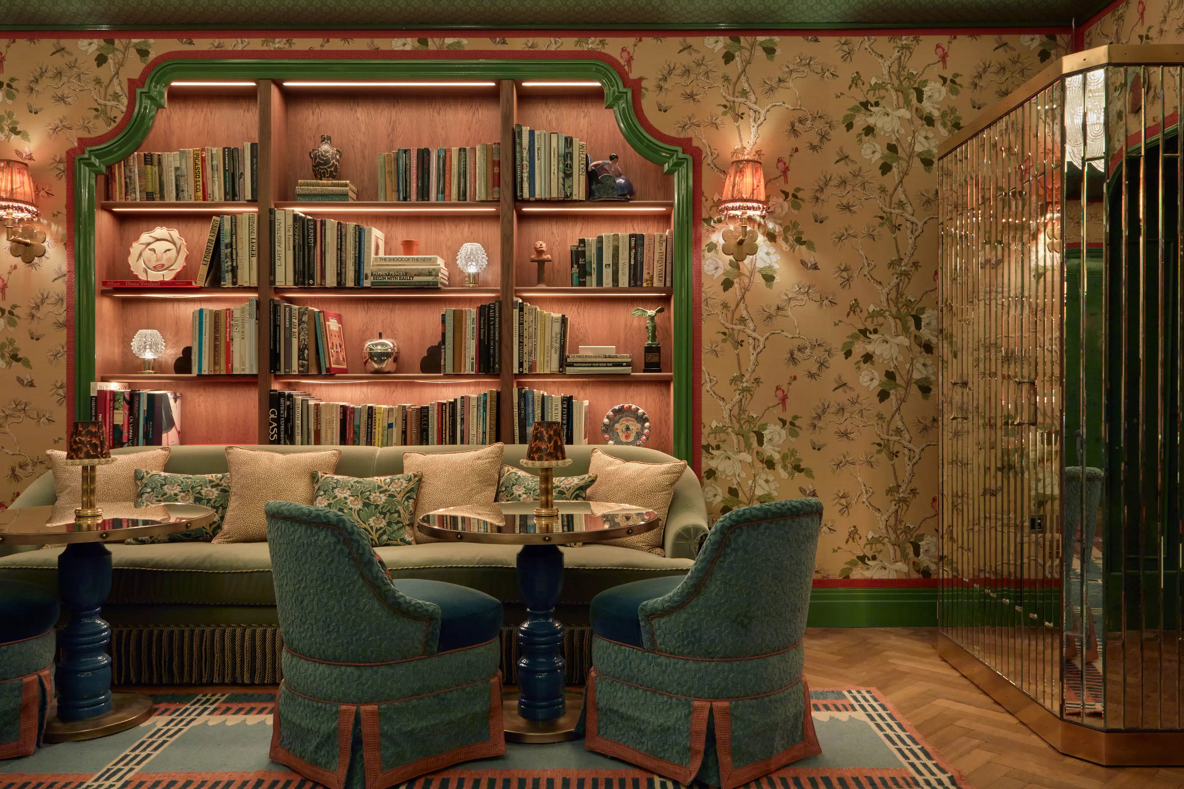 Elegant hotel library with patterned wallpaper, plush green furniture, and sophisticated British design